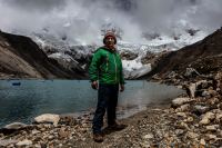Saúl Luciano Lliuya steht in grüner Jacke vor der Lagune Palcacocha