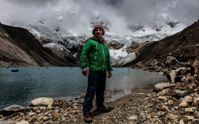 Saúl Luciano Lliuya steht in grüner Jacke vor der Lagune Palcacocha