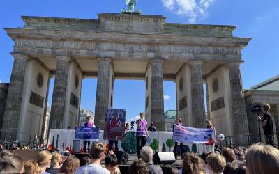 Menschen von Germanwatch bei einer Klimademo vor dem Brandenburger Tor mit Bannern und einem großen Foto von Saúl Luciano Lliuya